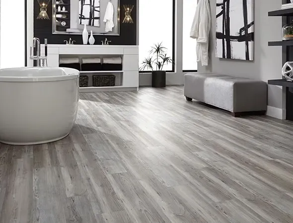 Modern bathroom with light wood flooring, featuring a freestanding white tub, black wall with dual sinks, shelves, decor items, and a gray bench. Luxurious ambiance.
