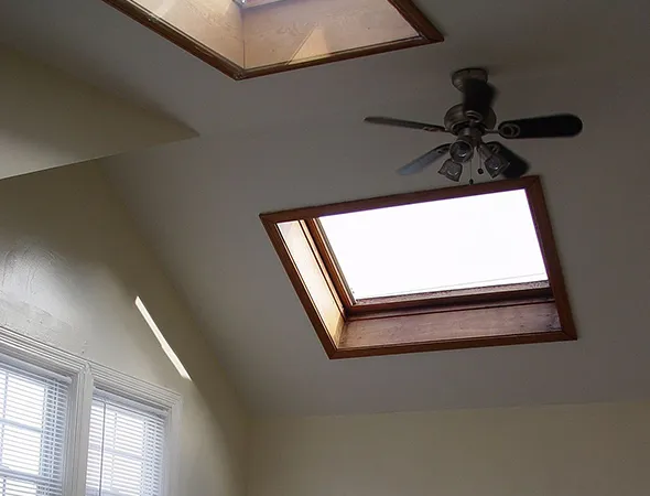 A roof featuring a sleek skylight beside a ceiling fan, blending natural light and airflow for a bright, comfortable space.