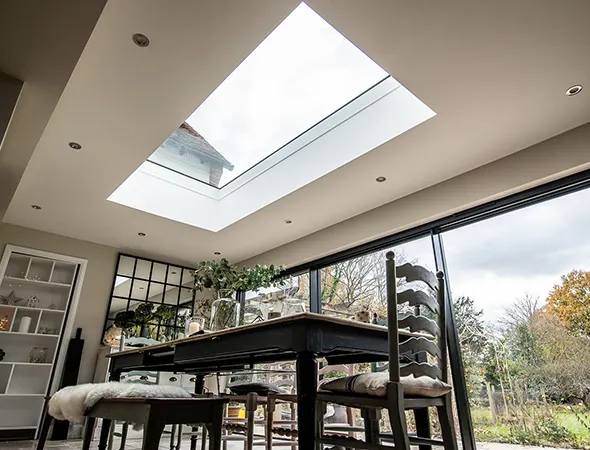 A sunny day beams natural light through the skylight above the dining table, brightening the room with a cheerful and cozy glow.
