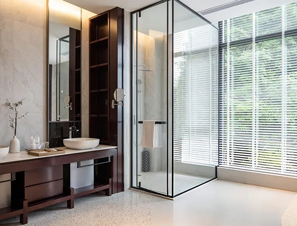 A stylish corner walk-in shower featuring clear glass panels and tiled walls, designed for space-saving elegance and accessibility.